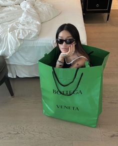 a woman sitting in a green shopping bag on the floor