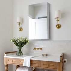 a bathroom with a sink, mirror and flowers on the counter in front of it