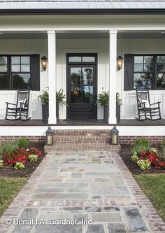 the front porch of a house with rocking chairs and flowers on the steps leading up to it