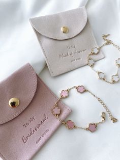 two pink purses sitting next to each other on a white bed with a gold chain