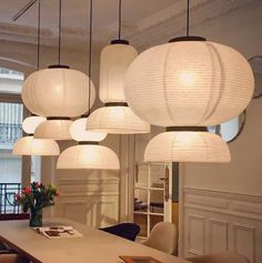 a room filled with lots of white lights hanging from it's ceiling above a dining table