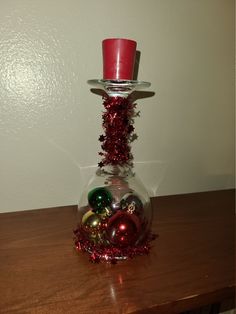 a glass vase filled with ornaments on top of a wooden table