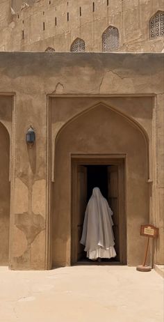 a person in a white veil standing at the entrance to a building