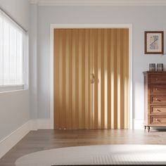 an empty room with a wooden door and dresser