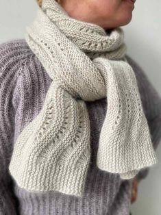 a woman wearing a gray sweater and white scarf