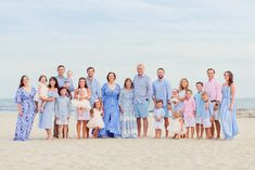 a group of people standing on top of a sandy beach next to the ocean in dresses