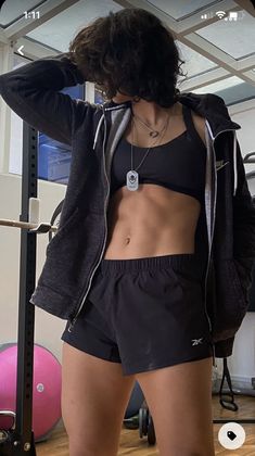 a woman standing in front of a mirror wearing black shorts and a sports bra top