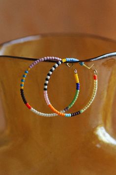 two bracelets with beads hanging from them on a wooden stand in front of a vase