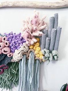 there are many crocheted flowers hanging on the wall next to a pair of shoes