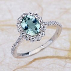 a ring with an aqua blue stone surrounded by white diamonds