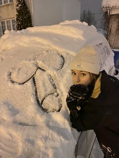 a woman standing next to a pile of snow