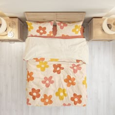 an overhead view of a bed with flowers on it and two night stands in the background