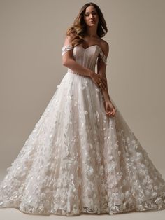 a woman in a wedding dress with flowers on the skirt and off the shoulder, posing for