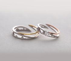 two gold and silver wedding rings with diamond accents on each band, sitting side by side