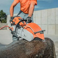 a man in an orange shirt is using a chainsaw