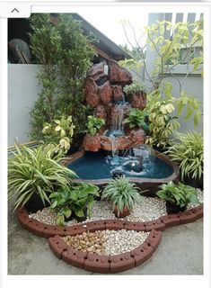 an outdoor fountain surrounded by plants and rocks