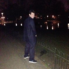 a man standing next to a fence at night