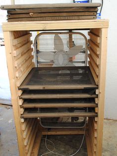 a bird cage with four birds in it and a fan sitting on top of the cage