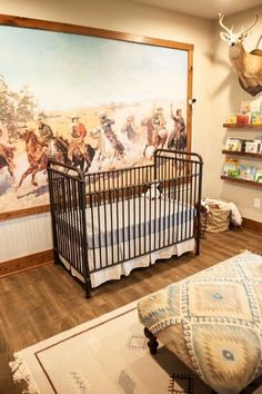 a baby crib in front of a large painting with cowboys on the wall behind it