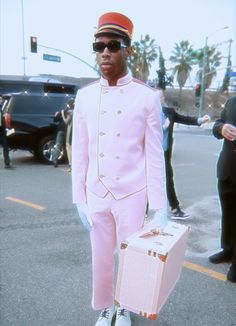 a man in pink suit and sunglasses holding a suitcase