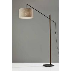 a floor lamp with a white shade on the top and a brown pole underneath it