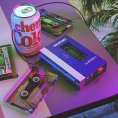 a table topped with different types of games and cassettes next to a can of soda