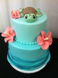 there is a blue cake with flowers on the side and a bird on top,