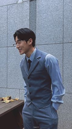 a man in a suit and tie standing next to a table