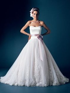 a woman in a white wedding dress with a pink bow on her head standing against a blue background