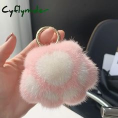 a person holding a pink furry ball with a ring on it's thumb and finger