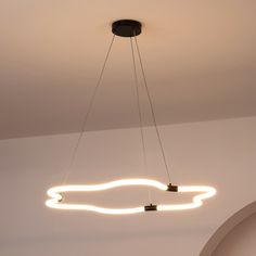 a modern light fixture hanging from the ceiling in a room with white walls and flooring