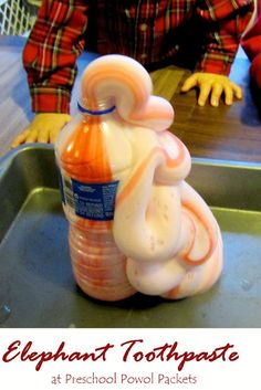 an elephant shaped toothpaste bottle sitting on top of a metal tray next to a child's hand