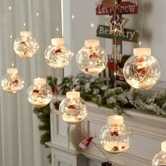 christmas decorations hanging from the ceiling in front of a fire place with lights on it