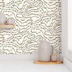 two white vases sitting on top of a counter in front of a wall paper