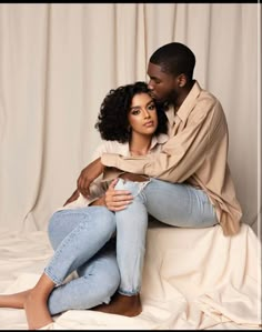 a man and woman sitting on top of each other in front of a white backdrop