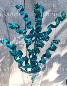 a vase filled with blue and green sequins on top of a wooden table