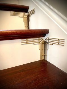 two wooden shelves on the side of a white wall next to a stair case with metal rods