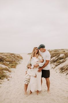 a man, woman and child standing on the beach with their arms around each other