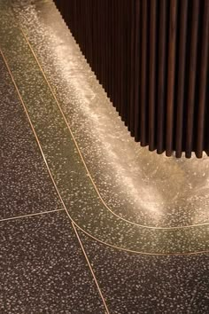 an umbrella is sitting on the ground next to a wall with metal slats in it