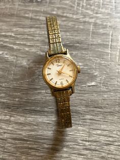 Vintage Women's Timex Quartz Watch. Adjustable stretch band.  Gold watch band, watch face is trimmed in gold with cream colored face and gold numbers numbers/time markings. Gold watch hands. There is some scratching on the face. Band is tarnished due to age. Unsure if it keeps time.  Engraved on back: Timex Base Metal Bezel Stainless Steel Back Water Resistant Philipines 377 BA Cell Gold Watch Band, Stretch Band, Stretch Bands, Watch Faces, Wrist Watches, Gold Studs, Gold Earrings Studs, Gold Jewellery, Base Metal