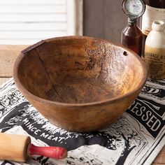 a wooden bowl sitting on top of a table next to bottles and a rolling pin