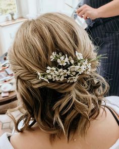 a woman is getting her hair done with flowers in the back of her head,