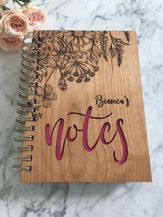 a wooden notebook with flowers and writing on it