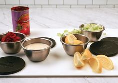 the ingredients to make an orange smoothie are displayed on a cutting board, with a can of juice in the background