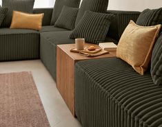 a living room filled with green couches and pillows on top of a wooden table