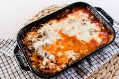 a casserole dish with cheese and meat in it on a checkered cloth