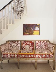 a living room filled with furniture and a chandelier hanging from the top of a stair case