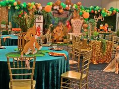 a decorated table with chairs and tables covered in green, gold and orange decorations for a jungle themed birthday party