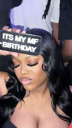 a woman holding up a sign that says it's my me - birthday in front of her face