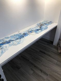 a white bench with blue paint on it in a room next to a light fixture